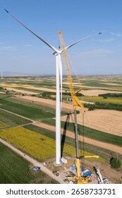 Wind turbine installation using a large construction crane. The assembly process of the turbine tower and rotor blades. Aerial view	
