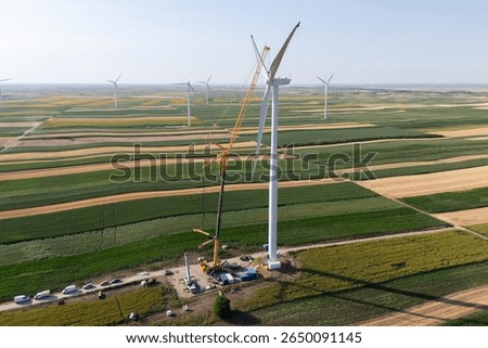 Wind turbine installation using a large construction crane. The assembly process of the turbine tower and rotor blades. Aerial view