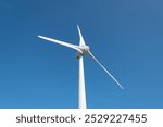 Wind turbine with its large blades generating electricity on a sunny day