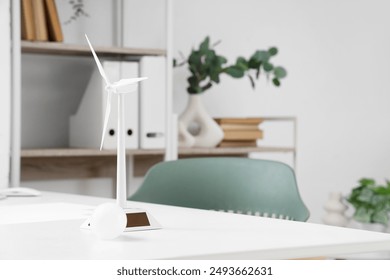 Wind turbine model with light bulb on engineer's table in office, closeup - Powered by Shutterstock