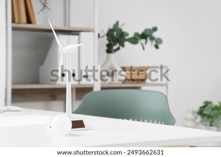 Wind turbine model with light bulb on engineer's table in office, closeup