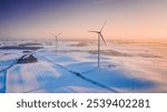 Wind turbine on snowy field in winter. Alternative energy in Poland. Aerial view of nature in winter.