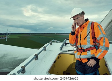 Wind turbine, phone call and man in electricity maintenance of industrial grid on production farm. Renewable energy, quality assurance and technician with smartphone at electrical windmill in field. - Powered by Shutterstock