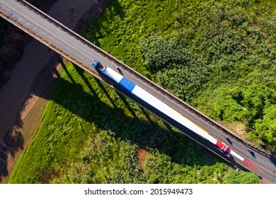 Wind Turbine Propeller Heavy Transporting On Trailer - Drone Aerial View With Beautiful Natural Landscape And Mountain Road With Green Trees