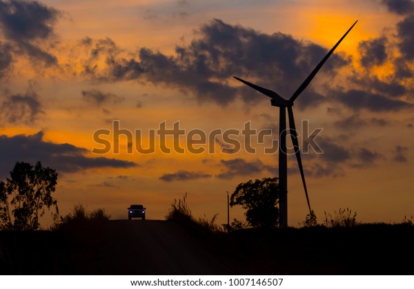 Wind turbine silhouette on suset background /\
Silhouette car on the road