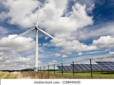 Wind Turbine At A Small Wind Farm Near Swindon In The UK In Bright Sunshine With Nearby Solar Panels.