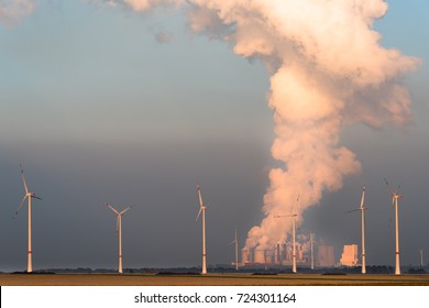 Wind Turbines And Coal Power Plant At Sunset. Representing The Contrast Of Renewable Energy And Fossil Fuels