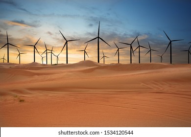 Wind Turbines In The Desert Suggesting Renewable Energy Concept With Sand Dunes At Sunset
