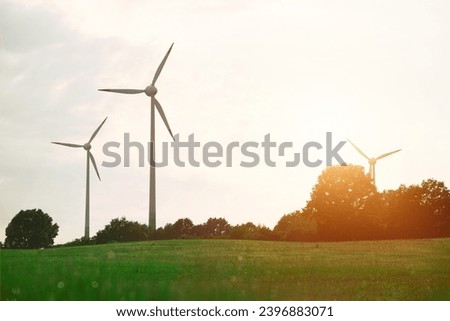 Wind turbines in a European forest produce electric power from renewable sustainable sources, creating a green and eco-friendly landscape in the summer season.