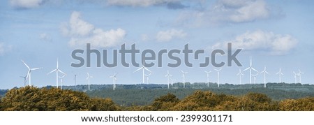 Wind turbines in a European forest produce electric power from renewable sustainable sources, creating a green and eco-friendly landscape in the summer season.