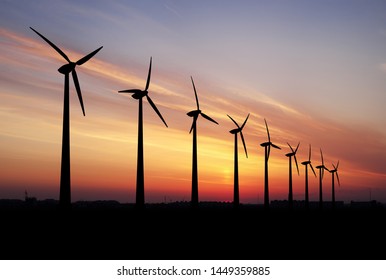 Wind turbines farm at beautiful orange sunset.