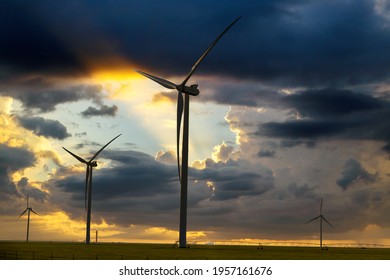 Wind turbines, wind farms silhouette at sunset with irrigation pivot water system on a farm field in Texas USA