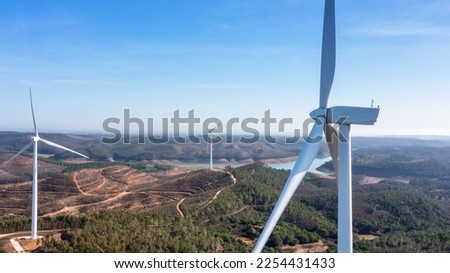 Wind turbines generate clean, green electricity in the fields of Portugal. With a view of the Bravura dam.
