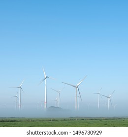 wind turbines in green meadow near aurich in german lower saxony on misty morning in august - Shutterstock ID 1496730929