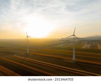 Wind turbines harnessing wind power during sunrise, set in an expansive agricultural landscape. Perfect for promoting clean energy and sustainability - Powered by Shutterstock