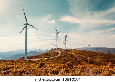 Windturbinen auf der schönen sonnigen Herbstlandschaft. Kurven Straße durch den Berg Eolic Park. Ökologische Stromerzeugung aus umweltfreundlicher Energie. Öko-Feld für Windparks