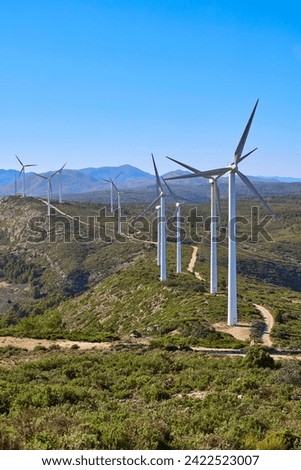 Wind turbines on beautiful sunny summer mountain landscape. Curvy road through mountain wind park. Green ecological power energy generation. Bunol wind farm, Spain.