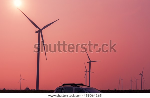 Wind turbines power generator with car on sunrise
at farmer field