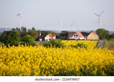 Wind turbines for renewable electricity, village houses and yellow rapeseed field. - Powered by Shutterstock