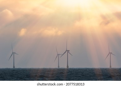 Wind Turbines Saving The Planet. Beautiful Spiritual Orange Pink Pastel Sky By Offshore Wind Farm At Sea. Tackling Climate Change. Sustainable Resource Renewable Energy From Wind Solar And Wave Power