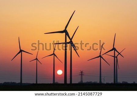 Wind turbines or wind wheels with a power pylon at sunset near Schülp in Dithmarschen, Schleswig-Holstein, Germany. Energy transition. Stockfoto © 