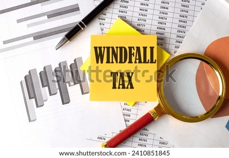 WINDFALL TAX text on sticky on the graph background with pen and magnifier