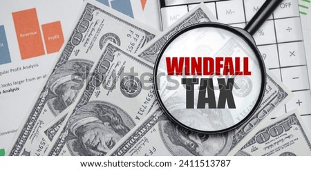 WINDFALL TAX word on magnifying glass with dollars and charts