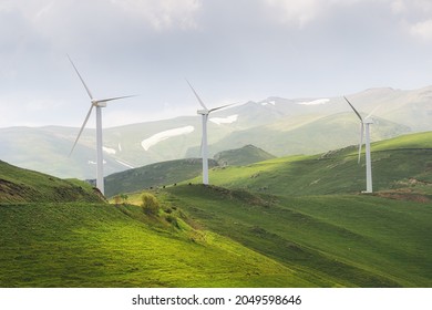 Windfarm generating electricity from the energy of strong winds blowing at the top of a high ridge in the countryside.