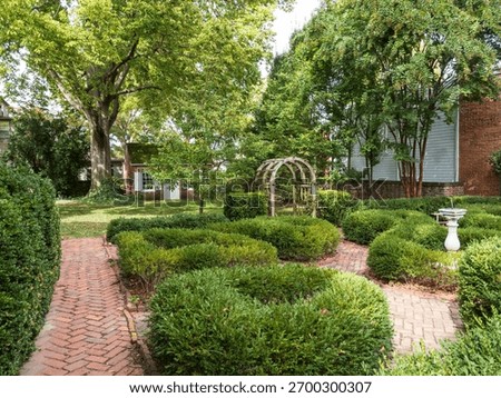 A winding brick path leads through the carefully manicured boxwood garden at the historic Amstel House in New Castle, Delaware.