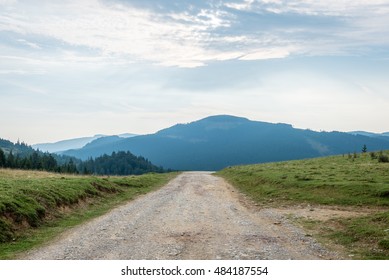 Winding Country Road With Clouds Above And Gravel Surface
