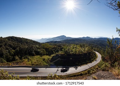 Winding Curvy Rural Road With Light Trail From Headlights Leading Through Countryside.