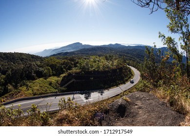 Winding Curvy Rural Road With Light Trail From Headlights Leading Through Countryside.