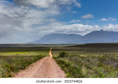 winding dirt road leading into the middle of nowhere with mountain background