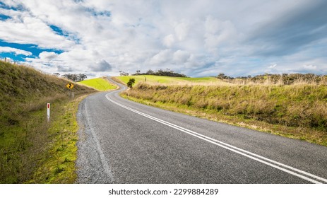 Winding empty road going up-hill through Adelaide Hills farmland during winter season, South Australia - Shutterstock ID 2299884289