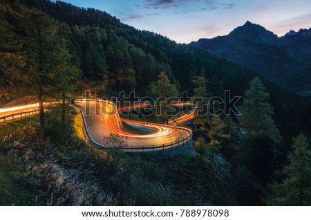 The winding mountain road with light tracks from cars at the evening, Maloja Pass, Switzerland