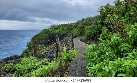 winding, paved coastal trail lined with lush vegetation and wooden fences, offering scenic ocean views under a cloudy sky.
35 kata kunci: - Powered by Shutterstock