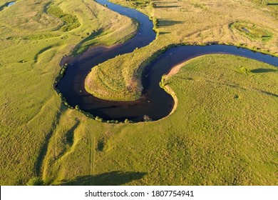 Winding river, aerial view. Summer landscape, top view. A green valley with a winding riverbed, water and grass