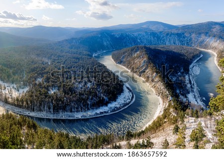 a winding river covered in snow. the water gradually freezes. First autumn frosts, nature of Russia, Siberia. Beautiful view from the mountain.