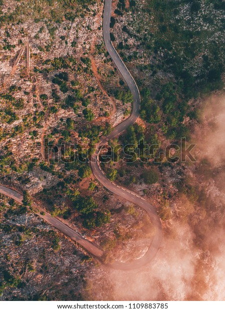 winding road above clouds drone shot for\
travel adventures