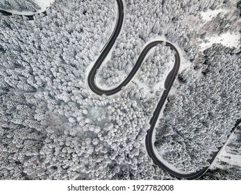 Winding Road Aerial View By Drone. Brasov, Romania. There Are Huge Snow Mountains And Long Winding Road In This Area. This Is A Great Place To Drive And Stop During A Road Trip.