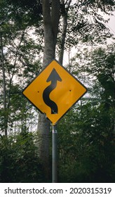 Winding Road Ahead Sign With Trees In The Background.