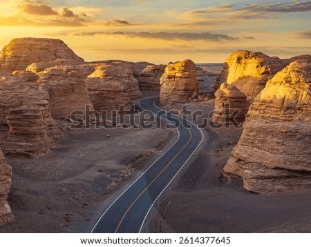 Winding road cuts through dramatic rock formations at sunset