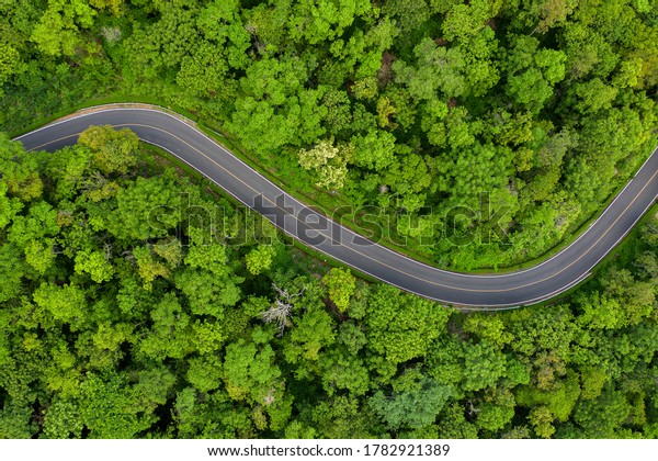 Winding road in the\
forest The top view of the beautiful Aerial view of asphalt road,\
the highway through the forest in the rainy season. For travel and\
nature driving\
\

