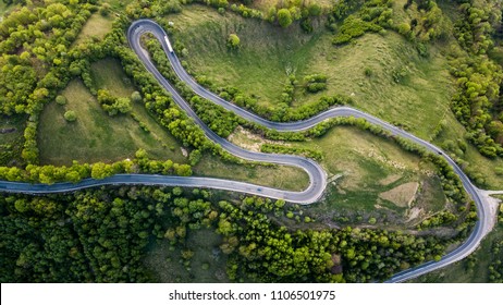 Winding road from high mountain pass, in spring time. Aerial view by drone . Romania	