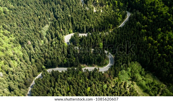 Winding road from high mountain pass, in spring\
time. Aerial view by drone .\
Romania