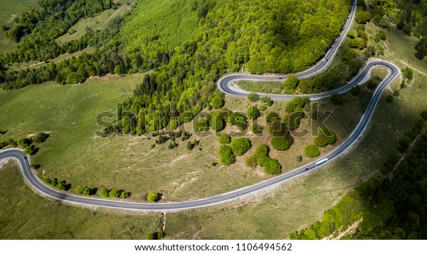Winding road from high mountain pass, in spring\
time. Aerial view by drone .\
Romania