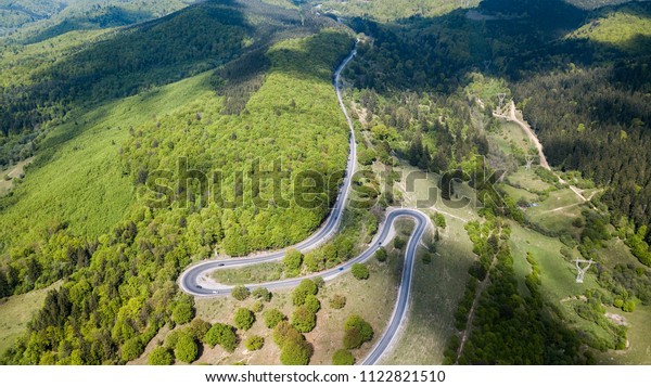 Winding road from high mountain pass, in\
summer time. Aerial view by drone .\
Romania	\
