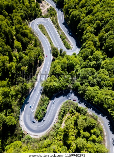 Winding road from high mountain pass, in summer\
time. Aerial view by drone .\
Romania