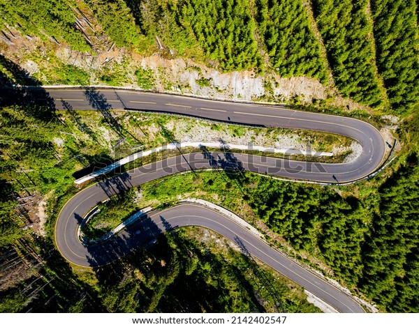 Winding road from high mountain pass, in summer\
time. Aerial view by drone.\
Romania