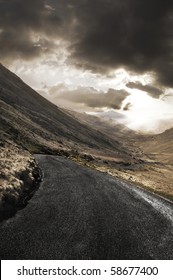 Winding Road Leading Through A Beautiful Rugged Landscape.